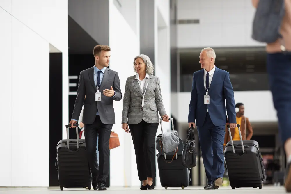 A professional traveler in an airport wearing a navy jacket with carry-on luggage.