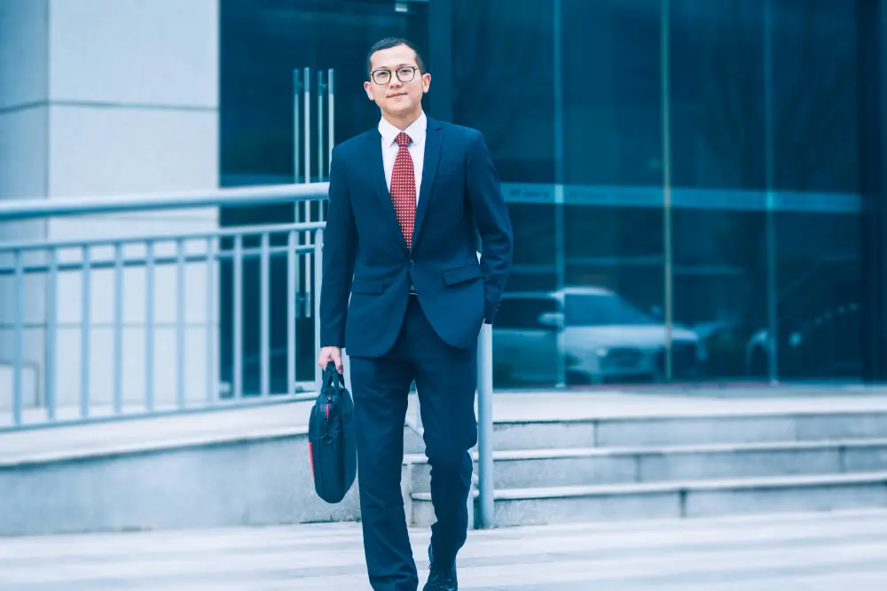 An Abu Dhabi executive walking through a modern business district wearing a well-fitted navy bespoke suit, carrying a briefcase, with contemporary Abu Dhabi architecture in the background.