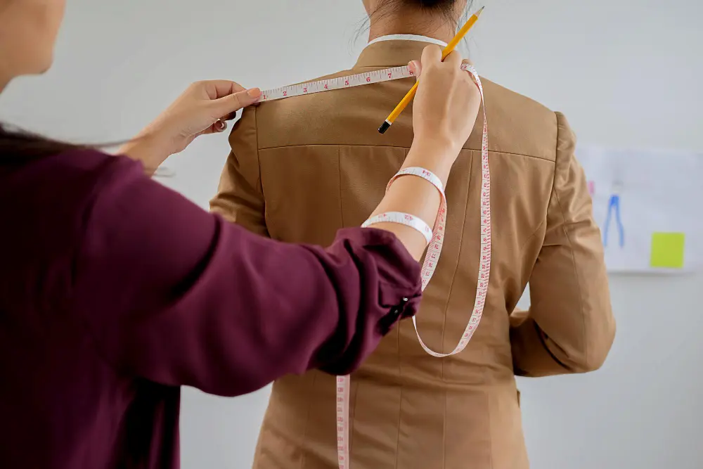 Tailor measuring shoulder width and posture.
